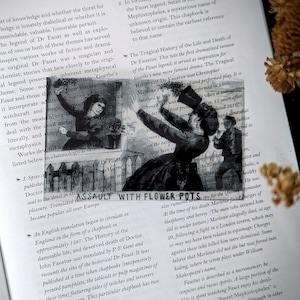 May include: A black and white illustration of a scene from the play "The Tragical History of Doctor Faustus" by Christopher Marlowe. The illustration depicts a man in a black hat and coat, with a white collar, raising his arms in the air. The man is surrounded by other figures, including a woman in a long dress and a man with a beard. The text "ASSAULT WITH FLOWER POTS" is visible at the bottom of the image.