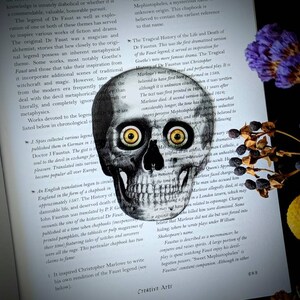 May include: A black and white illustration of a human skull with large, bright yellow eyes. The skull is superimposed on a page of text about the legend of Dr. Faustus. The text discusses the history of the legend and its various interpretations.