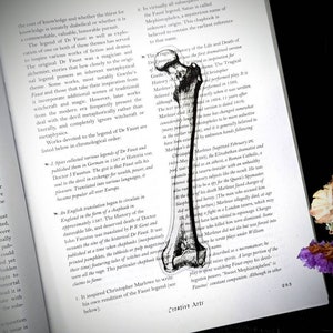 May include: A black and white illustration of a human skeleton leg bone. The image is from a book about the legend of Dr. Faust. The text on the page discusses the history of the legend and its various interpretations.