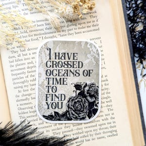 May include: A black and white sticker with a floral design and the text "I have crossed oceans of time to find you".