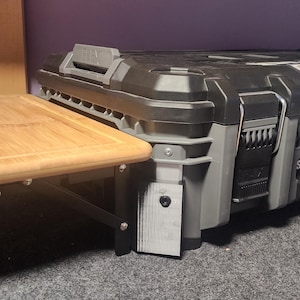 May include: A black and gray FLEX STACK PACK tool box with a light brown wooden table attached. The tool box has the FLEX logo on the front. The table is rectangular and has a light brown finish.