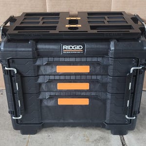 May include: Black RIDGID Pro Gear System 2.0 tool box with orange accents. The toolbox has a black top tray and metal latches. The text "RIDGID" is visible on the front of the toolbox.