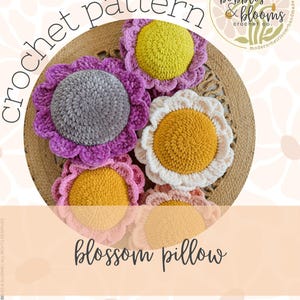 May include: A collection of handmade crochet flower pillows in various colors, including purple, pink, yellow, and white. The pillows are arranged on a woven surface. The image includes the text "crochet pattern" and "blossom pillow".