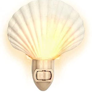 May include: A white seashell-shaped night light with a warm, yellow glow emanating from within. The night light has a simple on/off switch and a plug-in base, perfect for a bedroom or bathroom.