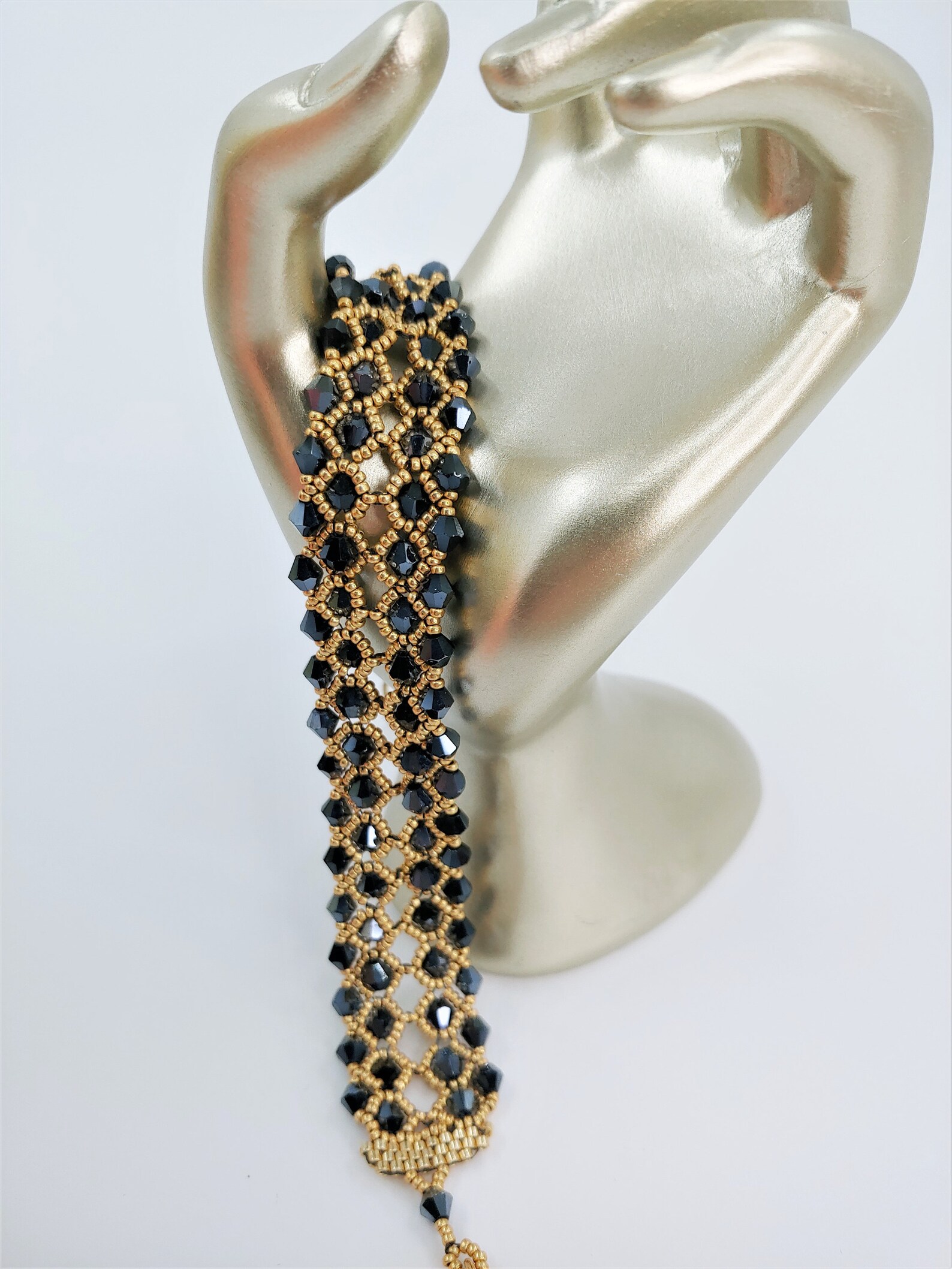 Gold and black beaded gothic bracelet displayed on silver mannequin hand