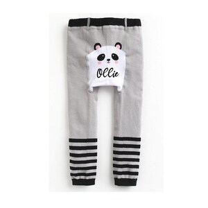 May include: Gray leggings with black and white stripes at the bottom. The leggings have a white panda bear patch on the back with the name "Ollie" written on it.