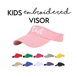 May include: Pink embroidered kids visor with the word "text" in white. The visor is available in 10 colors: red, green, pink, gray, yellow, beige, blue, white, purple, and black.