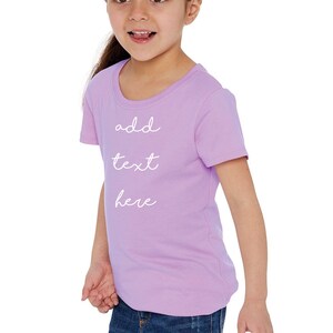 May include: A light purple short-sleeved t-shirt with the text "add text here" written in white cursive.