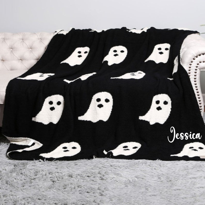 K&ouml;nnte beinhalten: Schwarze und wei&szlig;e Kuscheldecke mit einem Geistermuster. Die Decke ist aus weichem, flauschigem Material und hat den Namen "Jessica" in der rechten unteren Ecke gestickt.