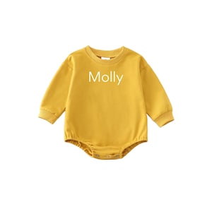May include: A mustard yellow long-sleeved baby onesie with the name "Molly" embroidered on the front.