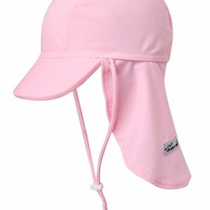 May include: A light pink sun hat with a long flap that can be tied at the back of the neck. The hat has a small brim and a white label with the text "Sun Vent".