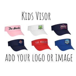 May include: Six different kids' visors with various colors and designs. The visors are all white, pink, red, blue, and navy blue. The visors have different text and logos on them, including "The Sharks", "All Star", "Basket", "The Whales", and "Soccer".