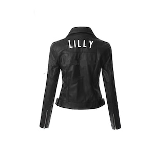 以下が含まれることがあります： 黒の革のジャケットで、背中に白い「LILLY」の文字があります。ジャケットはジッパーで閉じて、ウエストにベルトが付いています。