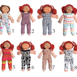May include: Eight Cabbage Patch Kids dolls wearing different patterned dungarees. The dolls have red hair and are wearing different coloured dungarees with various patterns, including floral, geometric, and striped.