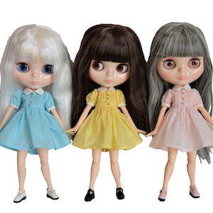 May include: Three dolls with long hair wearing different colored dresses. The doll on the left has white hair and is wearing a light blue dress. The doll in the middle has brown hair and is wearing a yellow dress. The doll on the right has gray hair and is wearing a pink dress.