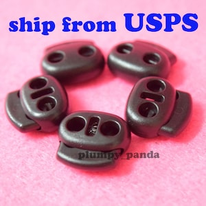 May include: Five black plastic toggle clasps with two holes each. The clasps are oval shaped and have a spring mechanism.