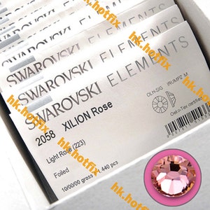 May include: A close-up of a packet of Swarovski Xilion Rose crystals. The packet is white with black text and a small image of a crystal. The text on the packet reads "Swarovski Elements 2058 Xilion Rose Light Rose (223) Foiled 10/00/00 gross 1,440 pcs".
