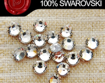 Puede incluir: Primer plano de un grupo de piedras de cristal redondas, transparentes y facetadas. Las piedras de cristal están dispuestas en un grupo suelto sobre un fondo de tela beige. El texto "HOTFIX SERIES 100% SWAROVSKI" es visible en la parte superior de la imagen.