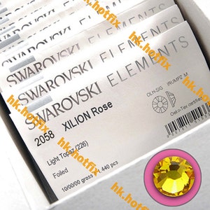 May include: A close-up of a package of Swarovski Xilion Rose crystals. The package is white with black text and a barcode. The crystals are light topaz in color and are 2.26 mm in size. The package contains 1,440 crystals.
