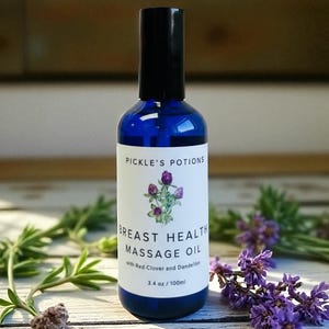 以下が含まれることがあります： Pickle's PotionsのBreast Health Massage Oilが入った青いガラス瓶。ラベルには花のイラストと「with Red Clover and Dandelion」の文字が描かれています。ボトルには100mlのオイルが入っています。