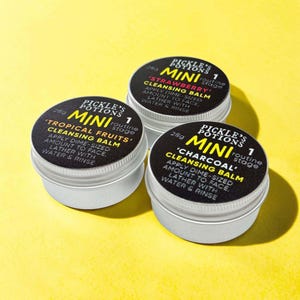 May include: Three round silver metal tins of Pickle's Potions mini cleansing balm, each 28g. The black labels feature yellow text reading 'MINI', '1 routine stage', and specific scent names: 'Strawberry', 'Tropical Fruits', and 'Charcoal'.