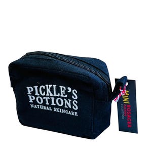 May include: A black zippered cosmetic bag with the text "PICKLE'S POTIONS NATURAL SKINCARE" in white. A small tag reads "MINI ROSACEA CALMING COLLECTION". The bag has a small loop attached to the zipper.
