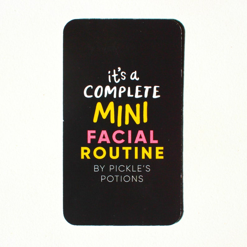 Op de afbeelding: Zwarte kaart met witte tekst die "it's a complete mini facial routine by pickle's potions" luidt. De woorden "mini" en "facial" zijn in roze en geel.