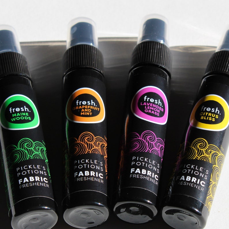 Puede incluir: Cuatro peque&ntilde;os frascos pulverizadores negros con etiquetas de diferentes colores. Cada etiqueta tiene la palabra "fresh." y un aroma diferente: Bosques de Maine, Pomelo y Menta, Lavanda Hierba Lim&oacute;n, y Felicidad C&iacute;trica. Cada frasco dice "Pickle's Potions Suavizante de Tela."