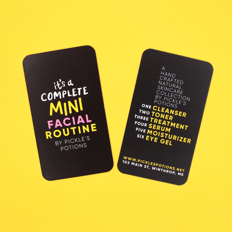 Op de afbeelding: Twee zwarte kaarten met witte tekst. De kaart links zegt "it's a COMPLETE MINI FACIAL ROUTINE BY PICKLE'S POTIONS". De kaart rechts somt de stappen op in een huidverzorgingsroutine: "ONE CLEANSER, TWO TONER, THREE TREATMENT, FOUR SERUM, FIVE MOISTURIZER, SIX EYE GEL". De kaart bevat ook het websiteadres "WWW.PICKLESPOTIONS.NET" en het adres "103 MAIN ST, WINTHROP, ME".