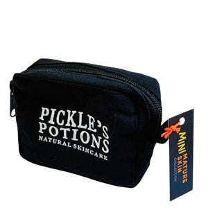 May include: Black zippered cosmetic bag with the text "PICKLE'S POTIONS NATURAL SKINCARE" in white. A small tag attached reads "MINI MATURE SKIN COLLECTION". The bag is rectangular and appears to be made of canvas.