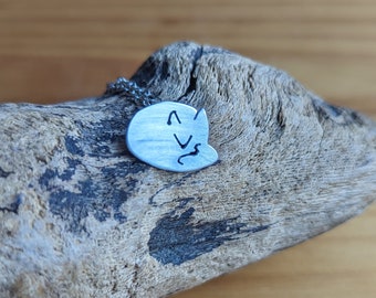 May include: A silver necklace with a pendant shaped like a sleeping cat. The pendant is on a piece of driftwood.