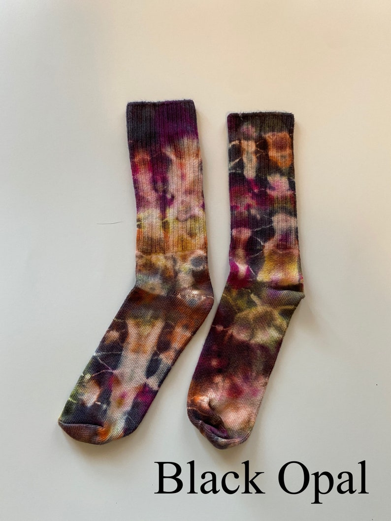 May include: A pair of colorful socks with a tie-dye pattern in shades of purple, orange, and black. The socks are labeled "Black Opal".