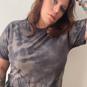 May include: A black and gray tie-dye t-shirt with a relaxed fit.