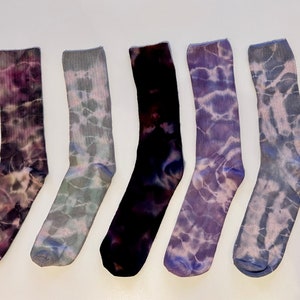 May include: Five pairs of tie-dye socks in various shades of purple, blue, and green. The socks are all crew length and have a ribbed texture.