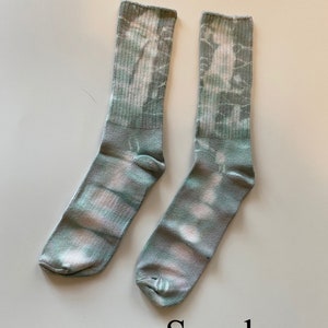 May include: A pair of green and white tie-dye socks with the word "Seaglass" written below them.