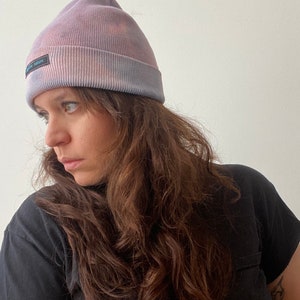 May include: A purple and pink tie-dye beanie with a black "Native Fabric" label.