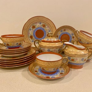 May include: A vintage tea set with a floral pattern in shades of blue, red, and gold. The set includes a teapot, creamer, sugar bowl, four teacups, and four saucers.