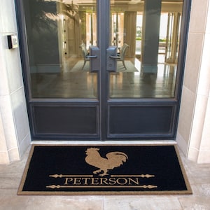 Puede incluir: Una alfombra de bienvenida negra con una silueta de gallo marrón y el texto "PETERSON" en una fuente marrón. La alfombra está delante de una puerta doble de vidrio con marcos negros.