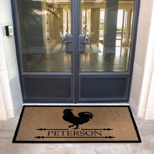 Puede incluir: Una alfombra de coco marrón con una silueta de gallo negro y el texto "PETERSON" en letras negras.