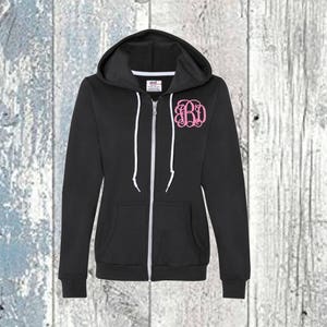 May include: A black zip-up hoodie with a white zip and white drawstrings. The hoodie has a pink monogram on the front that says "BD".