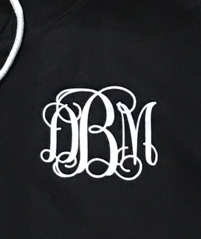 May include: Black hoodie with a white monogram of the letters "DBM" in a cursive font.
