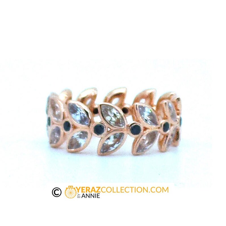 Puede incluir: Un anillo de oro rosa con un delicado dise&ntilde;o de hojas y piedras preciosas transparentes. El anillo est&aacute; engastado con piedras preciosas negras entre cada hoja.