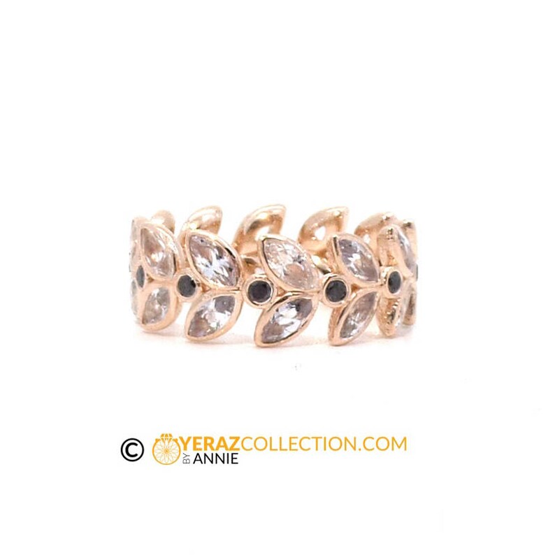 Puede incluir: Un anillo de oro con un delicado dise&ntilde;o de hojas y piedras blancas. El anillo est&aacute; engastado con piedras negras entre las hojas.