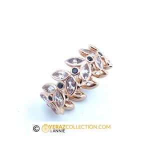 Puede incluir: Un anillo de oro con un dise&ntilde;o de hojas y piedras preciosas transparentes y negras.
