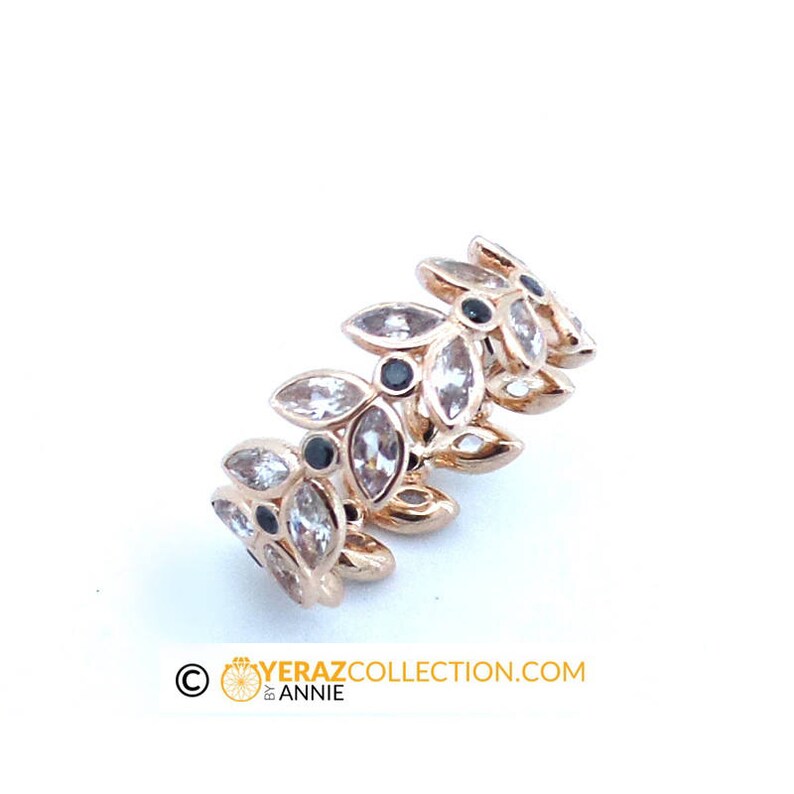 Puede incluir: Un anillo de oro con un dise&ntilde;o de hojas y piedras preciosas transparentes y negras.