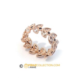 Puede incluir: Un anillo de oro rosa con un delicado dise&ntilde;o de hojas y piedras preciosas transparentes y negras. El anillo es una pieza llamativa y ser&iacute;a una hermosa adici&oacute;n a cualquier colecci&oacute;n de joyas.