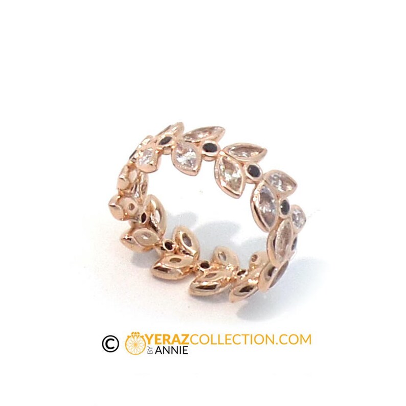 Puede incluir: Un anillo de oro rosa con un delicado dise&ntilde;o de hojas y piedras preciosas transparentes y negras. El anillo es una pieza llamativa y ser&iacute;a una hermosa adici&oacute;n a cualquier colecci&oacute;n de joyas.