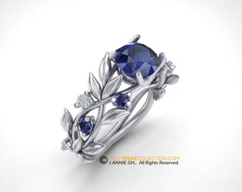 Puede incluir: Un anillo de plata con una piedra preciosa de zafiro azul rodeada de un diseño de hojas y zafiros azules y diamantes más pequeños.