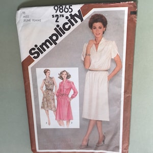 May include: Vintage Simplicity sewing pattern packet. The packet features a woman in a white dress with a belt. The packet also shows illustrations of two other dress styles. The text on the packet reads "9865" and "Miss Jeune Femme".