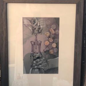 May include: Framed artwork depicting a person using a wine opener on a bottle. The image is in grayscale, with a focus on the hands and the wine opener. Corks are scattered in the background. The frame is a dark gray color.